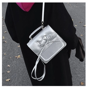 Silver metallic crossbody bag with bow detail and mesh overlay shown on a model