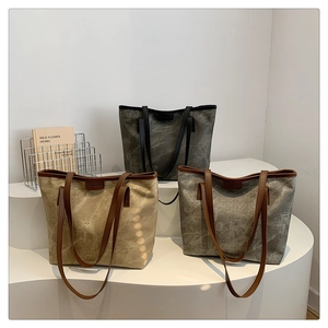 Three minimalist canvas tote bags in beige, grey, and charcoal displayed on white steps