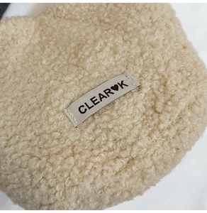 Macro detail of plush cream faux fur texture with a Clear Heart K woven label