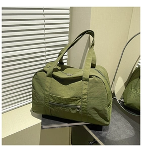 Detail of army green nylon travel tote bag showing front zip pocket and fabric texture