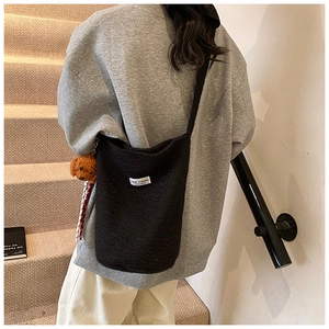Winter black fleece bucket bag with bear pendant shown on model in a modern interior