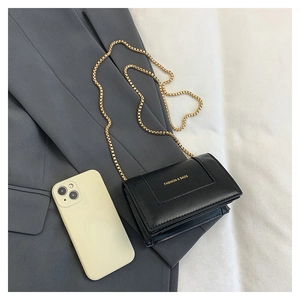 Detail view of mini black leather crossbody bag with gold chain and size reference