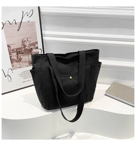 Detail showing thick canvas tote bag straps and front pocket with gold metal snap button