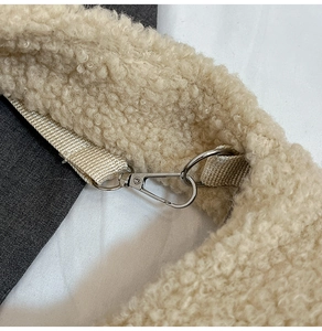 Detailed close-up of beige faux shearling texture with silver metal swivel hooks on bag