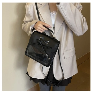 Detail of black ita bag featuring lace-up bow design and transparent display window