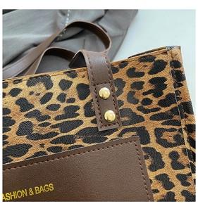 Detail of leopard print tote bag featuring brown faux leather stitching and gold rivets