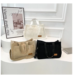 Detailed close-up of corduroy tote bags with multi-pockets in cream, khaki, and black