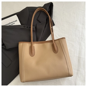 Detail showing high-quality khaki leather texture and white stitching on a minimalist tote bag