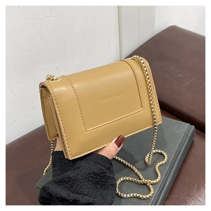 Detailed macro view of khaki leather bag featuring golden fashion text and chain strap