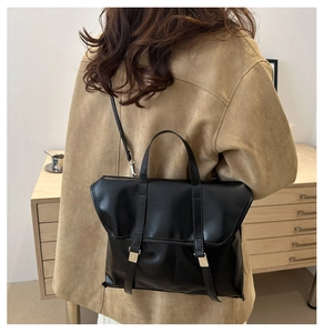 Detail of vintage black briefcase bag showing matte texture and gold metal buckles