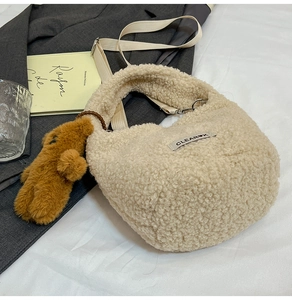 Detail of off-white faux shearling bucket bag with bear charm and wide strap
