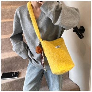 Close-up of fluffy yellow faux fur bucket bag with LOVE FASHION label and teddy charm