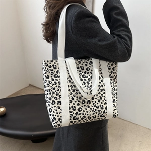 Grand sac cabas en toile à imprimé léopard avec bretelles blanches porté par une femme