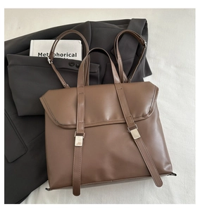 Detail view of the brown leather backpack with silver hardware buckles and bottom studs