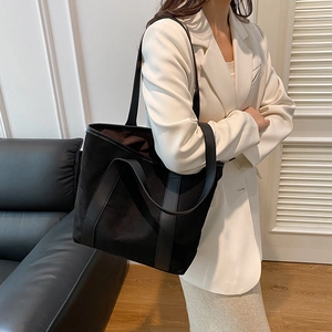 Minimalist black suede tote bag with leather trim and large capacity shown on shoulder