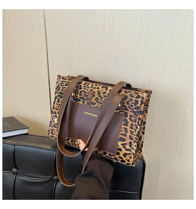 Detail of leopard print tote bag featuring a brown leather pocket with embossed text