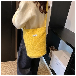 Side view of a fluffy yellow wool bucket bag with 'LOVE FASHION' label and long strap
