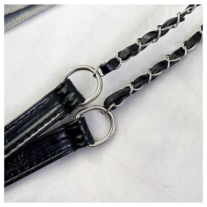 Detail of black glossy leather shoulder strap with silver ring and braided chain links