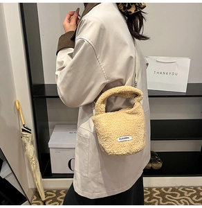 Detail view of plush beige faux shearling bucket bag showing texture and tag