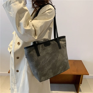 Grey marble texture tote bag with black straps and fashion label on beige trench coat