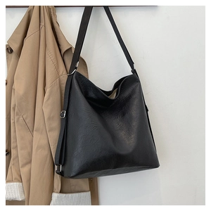 Detail of black tote bag with wrinkled leather texture and wide adjustable shoulder strap