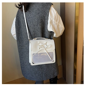 Detail of white leather shoulder bag featuring a cute bow and transparent mesh pocket