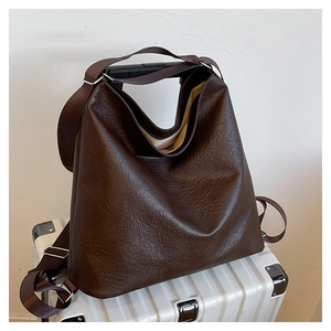 Detailed texture of a vintage dark brown tote bag hanging on a silver metal suitcase