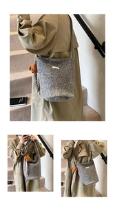 Detail of grey wool bucket bag with a cute brown teddy bear charm and logo patch