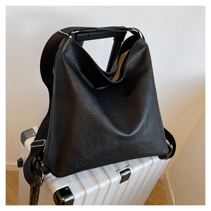 Close-up of black leather tote bag sleeve attached to a white suitcase handle for travel