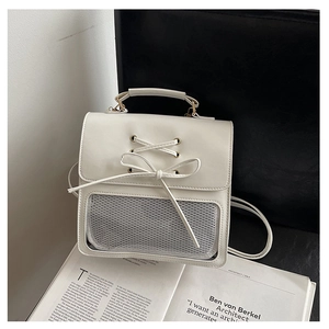Detail of cream backpack featuring a decorative bow and a unique semi-transparent mesh window