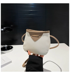 Détail d'un sac bandoulière bicolore avec texture grainée et décor métallique