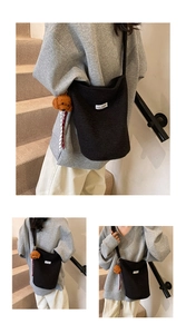 Detail of black plush bucket bag featuring a cute brown bear charm and white fashion label