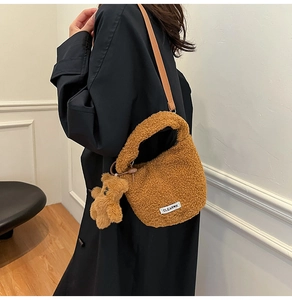 Detail of plush faux lamb wool bucket bag in brown with cute teddy bear charm