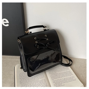 Close-up of black Ita bag featuring ribbon lace-up detail and rectangular clear window
