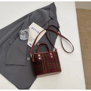 Close-up of retro plaid wool handbag with leather handles and gold rivet details