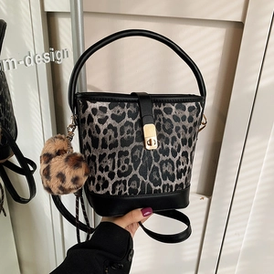 Leopard print bucket bag with black leather trim and plush charm for women