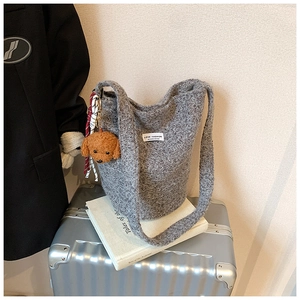 Detail of grey wool-knit bucket bag with Love Fashion label and teddy bear charm