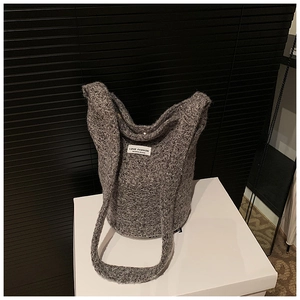 Detail showing the gray chunky knit wool blend texture and white brand label on bucket bag