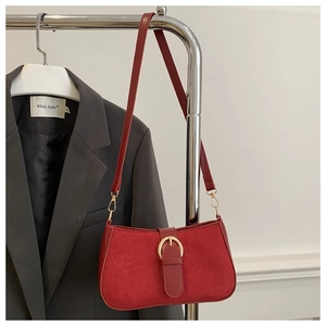 Detail of red suede hobo bag with vintage gold buckle on grey blazer background