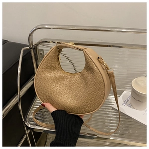 Close-up of beige woven crescent bag texture with golden zipper and red nail model