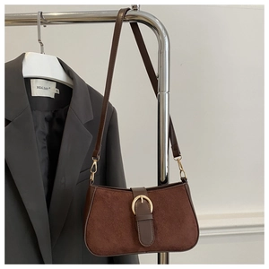 Close-up of vintage brown suede shoulder bag with a gold buckle on a blazer background