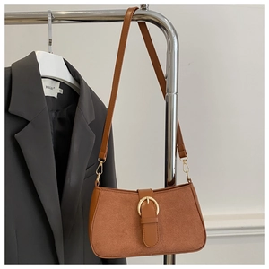 Close-up of caramel suede hobo bag with a prominent gold horseshoe buckle detail