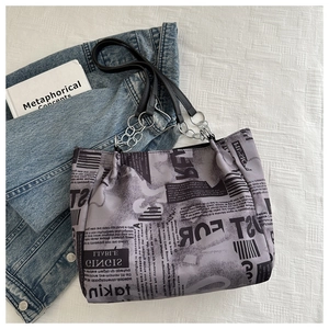 Detailed shot of newspaper print tote bag with silver chain strap and leather handle