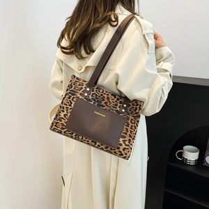 Fashionable leopard print tote bag with brown leather pocket shown on a model's shoulder