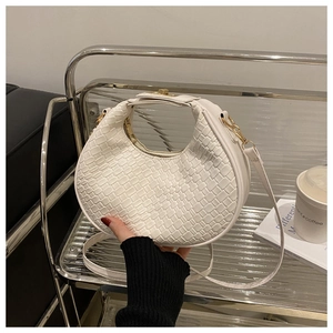 Detail shot of the white woven texture and gold metal hardware on the crescent bag