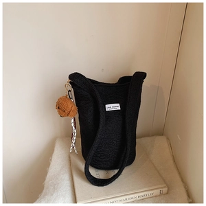 Detail of black teddy wool bucket bag with woven label and cute brown dog charm