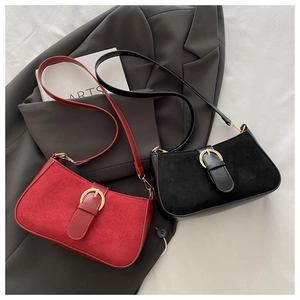 Detail of vintage suede underarm bag with gold horseshoe buckle in red and black