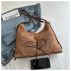 Nahaufnahme der braunen Wildledertasche mit Schmetterlings-Applikation und Schnürung