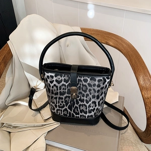 Detailansicht der Beuteltasche mit Leopardenmuster und goldenem Drehverschluss auf Stuhl