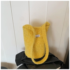 Detailed view of the bright yellow faux fur bucket bag with a white woven label detail
